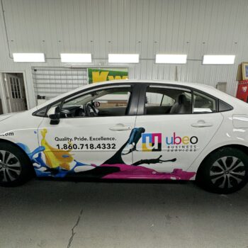 Side of a vinyl car wrap with company information and colorful graphics