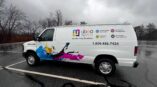 Side of a van that is wrapped in panel vinyl with company details and colorful graphics.