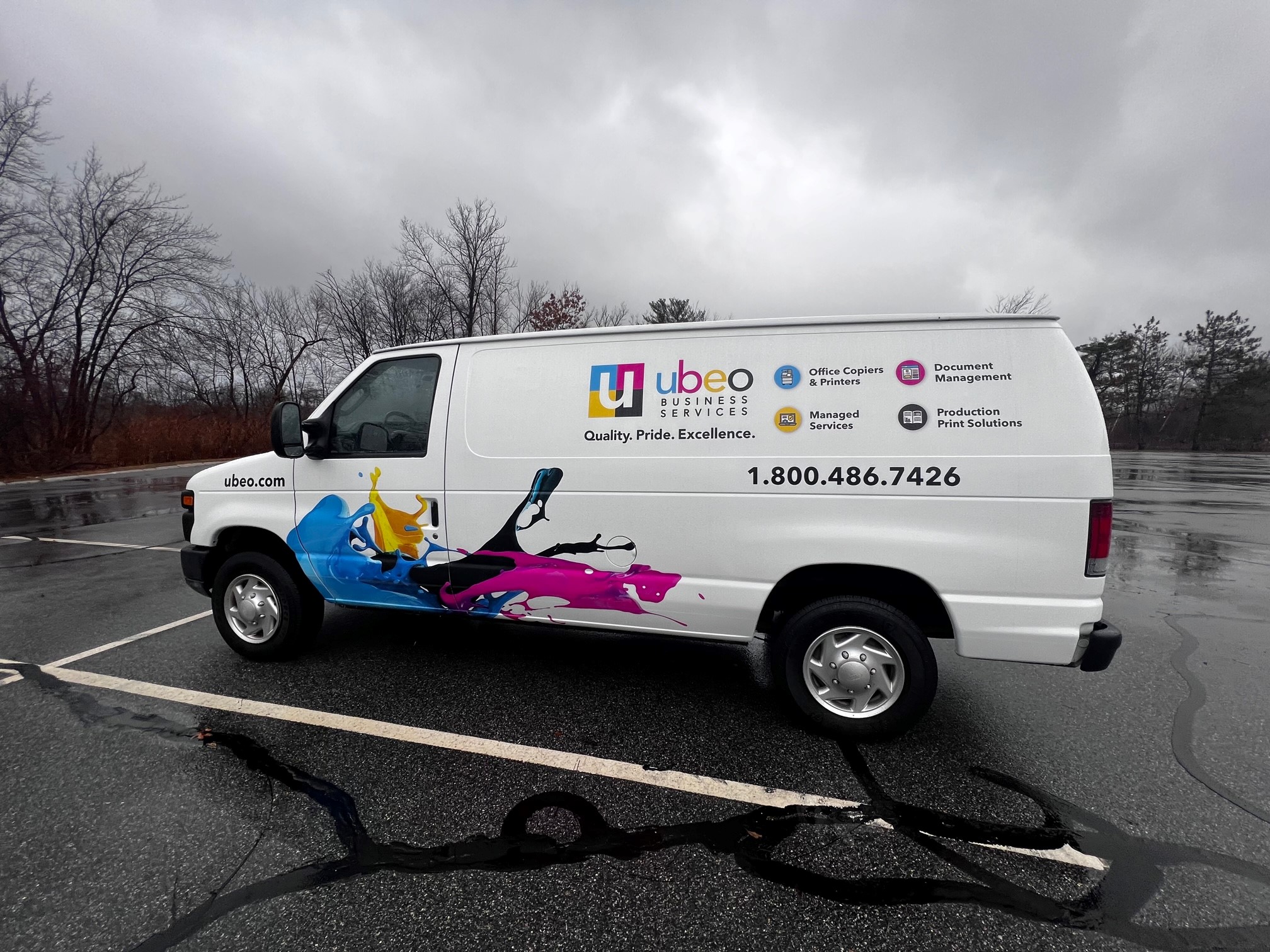 Side of a van that is wrapped in panel vinyl with company details and colorful graphics.