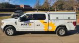 Side of a truck with vinyl wrapping of the company logo, yellow graphics and promotional text.