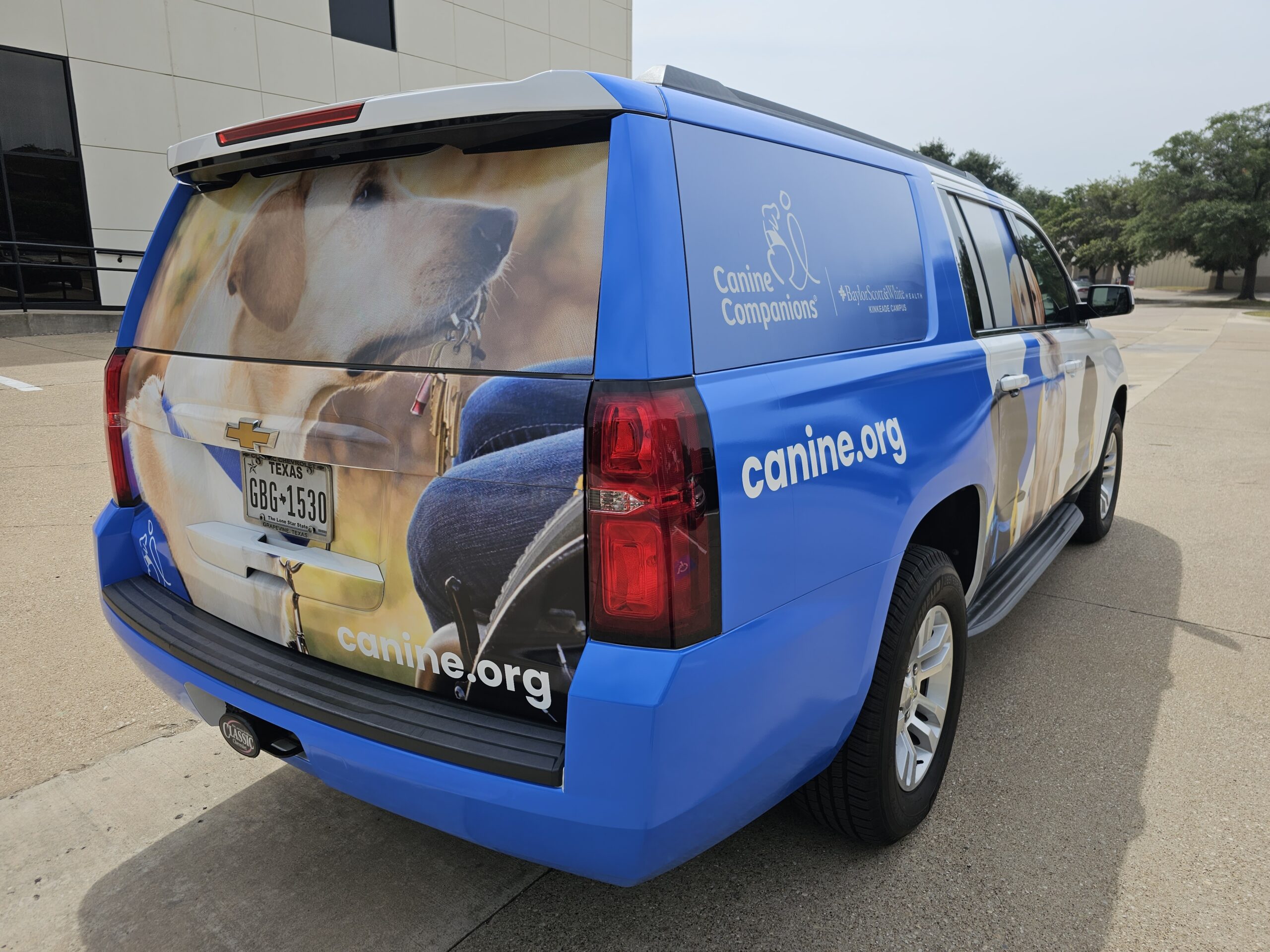 Back right side of an SUV that is wrapped with promotional graphics of a dog for Canine Companions.