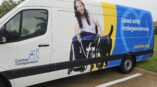 Left side of an van with graphics on it of a woman in a wheelchair with a dog and the words 