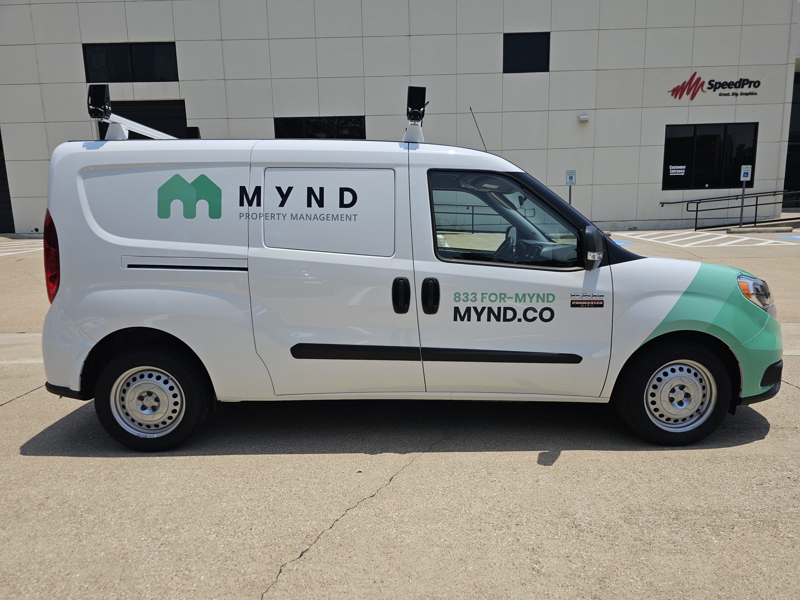 Right side of a van that is wrapped in green graphics with a logo and promotional text.