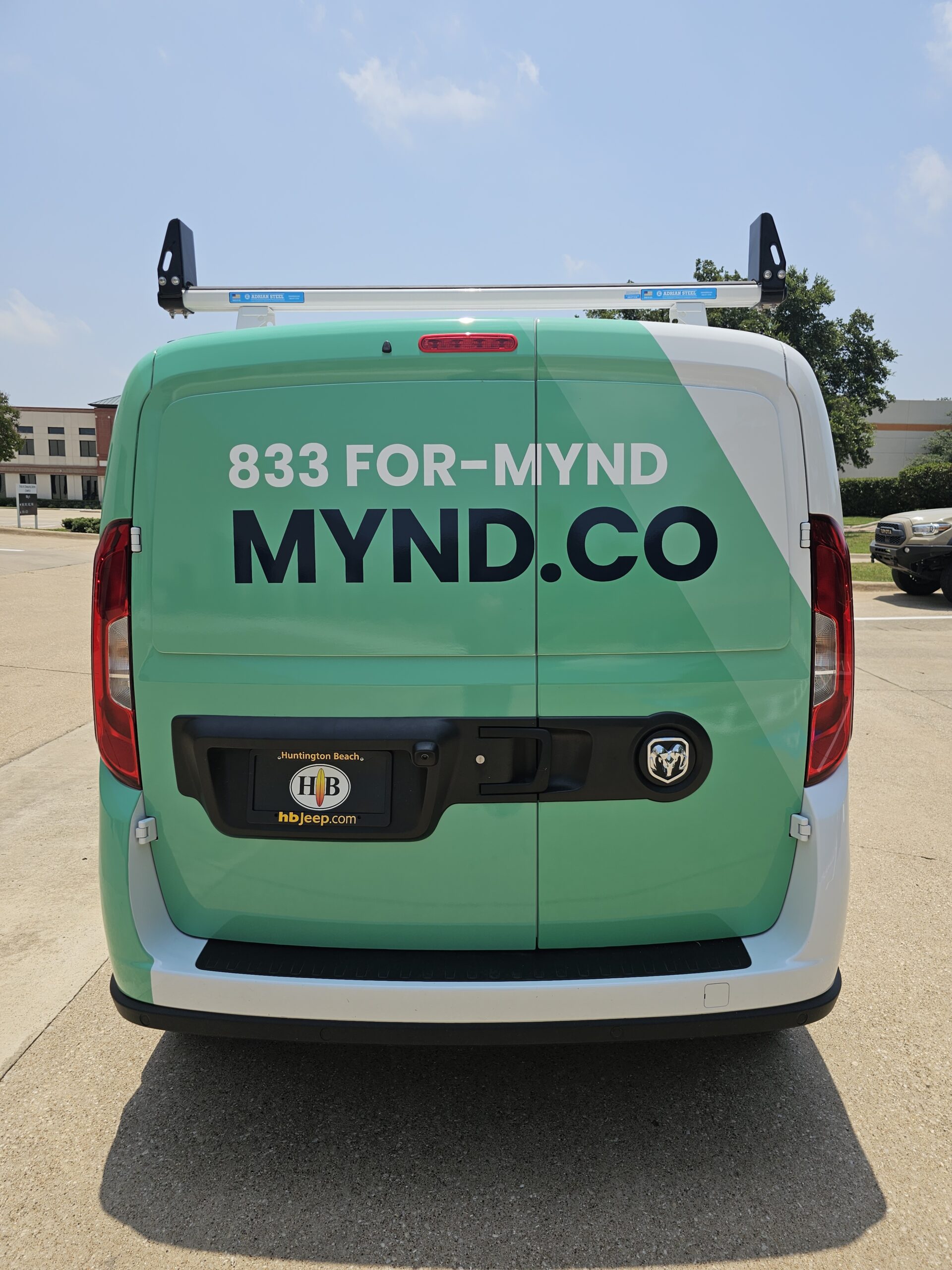 Back of a van that is wrapped in green graphics with promotional text