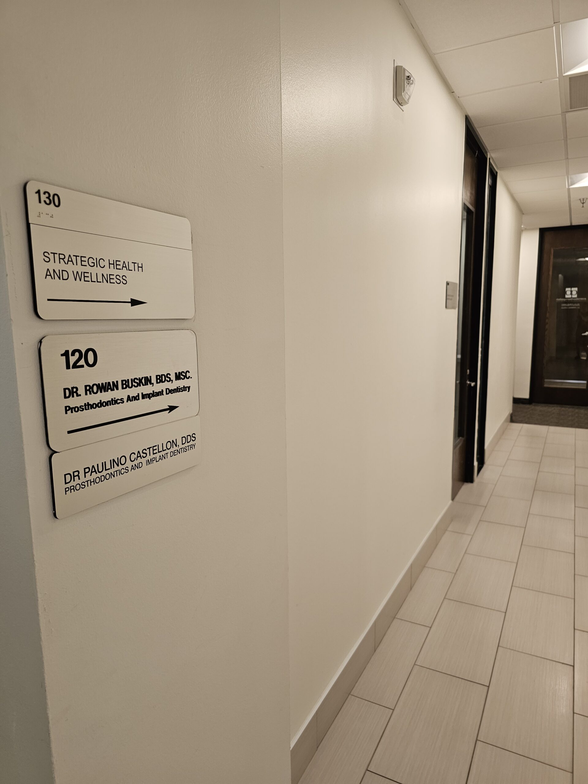 Directional ADA signage in an office that is brushed metal looking on a wall.
