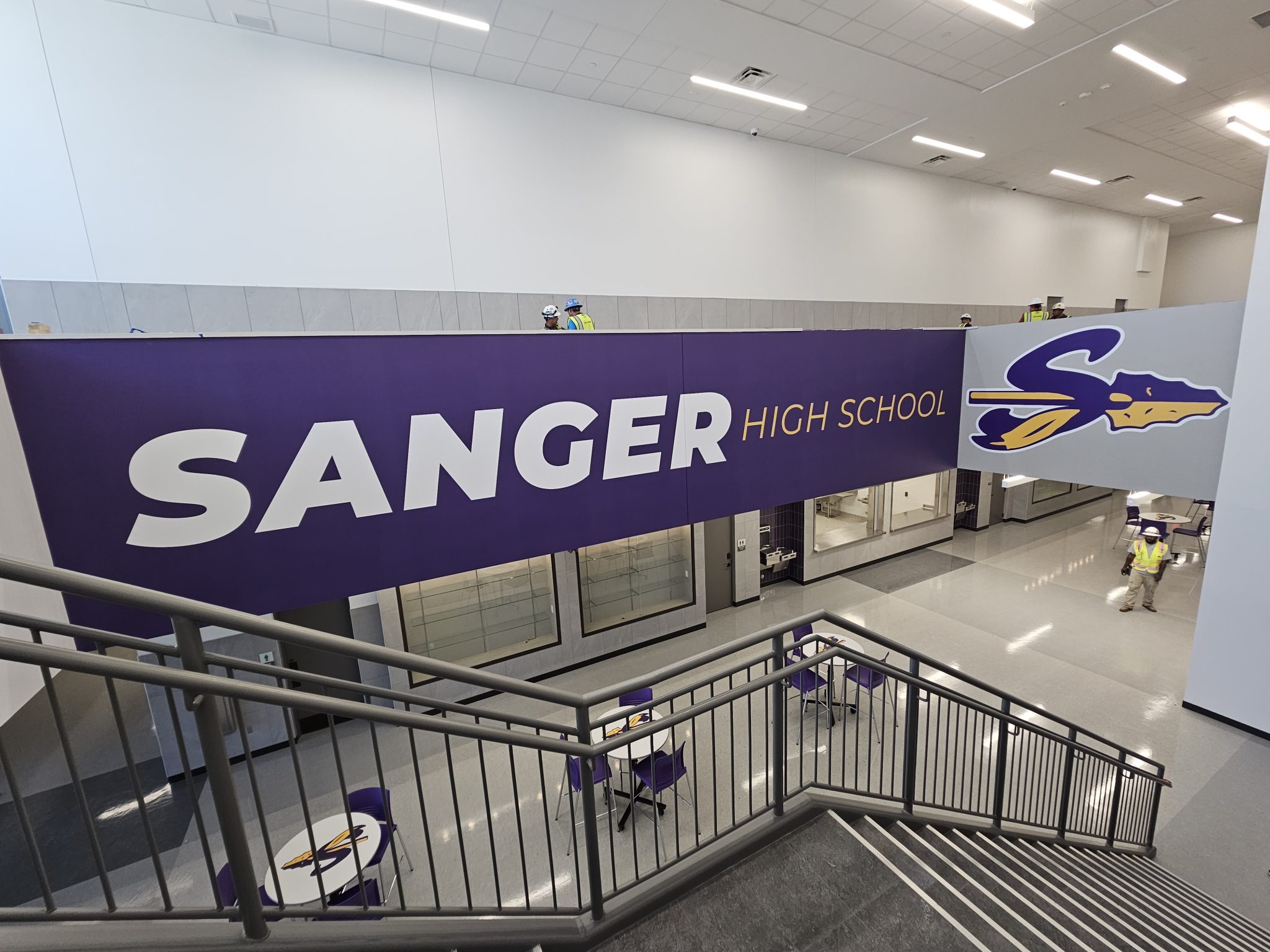 Custom large format wall mural and floor graphics for Sanger High School's commercial interior, featuring purple branding by SpeedPro Irving.