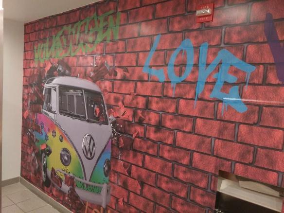 Printed wall of spray painted bricks and rainbow Volkswagen van 