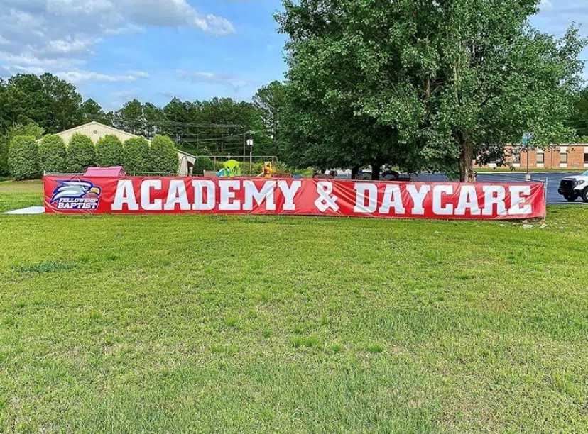 Advertising banner on grass promoting academy and daycare services outdoors