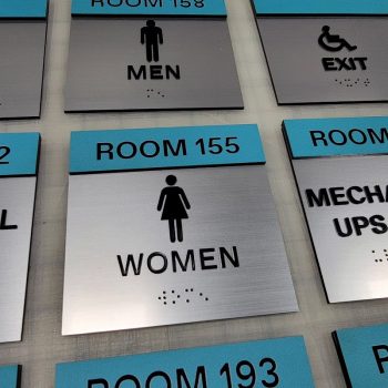 Brushed metal ADA bathroom signs with blue headers and black symbols in Chicago, IL.