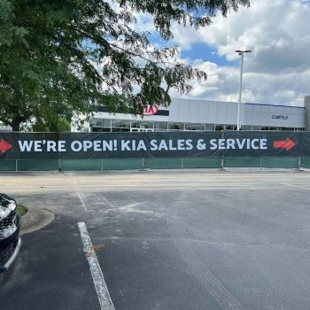 Large black vinyl banner with white and red text on fence in Chicago, IL.