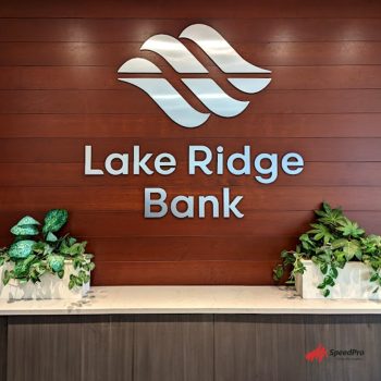 Dimensional metal letters and logo sign on wood panel wall with plants in Chicago, IL.