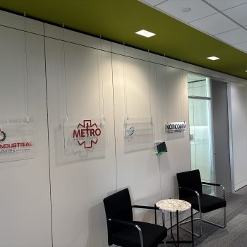 Clear acrylic hanging signs with printed logos in an office hallway in Chicago, IL.