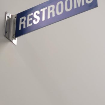 Blue rectangular restroom wall sign mounted on metal bracket in Chicago, IL.