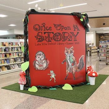 Large fabric display with printed graphics and 3D elements in a Chicago, IL library.