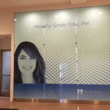 woman smiling for dental company window graphic