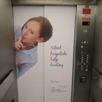 An elevator wrap that reads Silent Hospitals Help Healing with a lady putting her finger up to her mouth