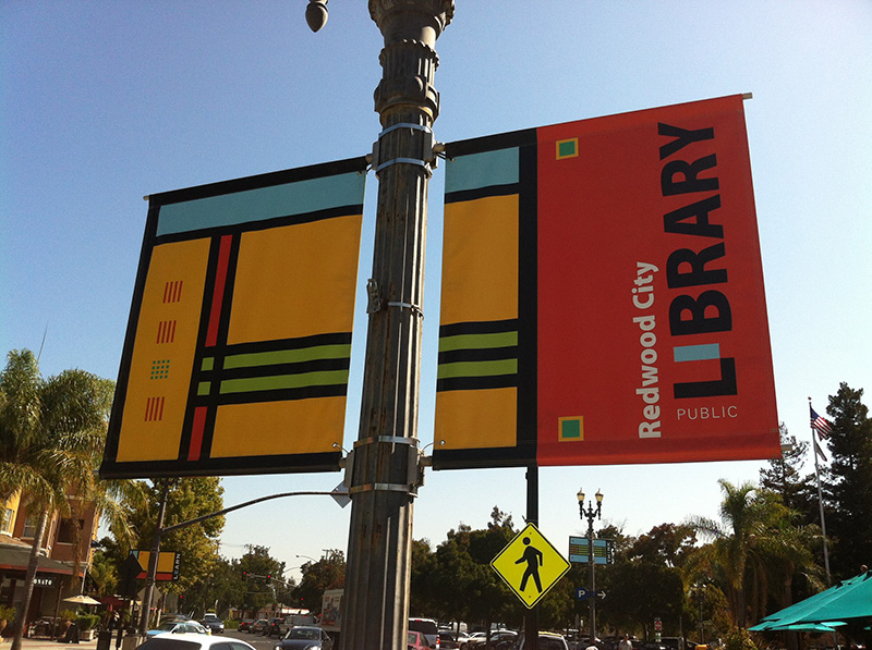 A custom vinyl banner for Redwood City Public Library that is hung on a street light