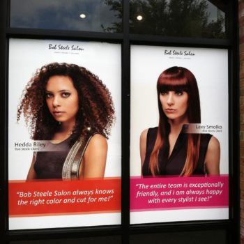 Window decals for Bob Steele Salon with headshots of two clients and testimonials 