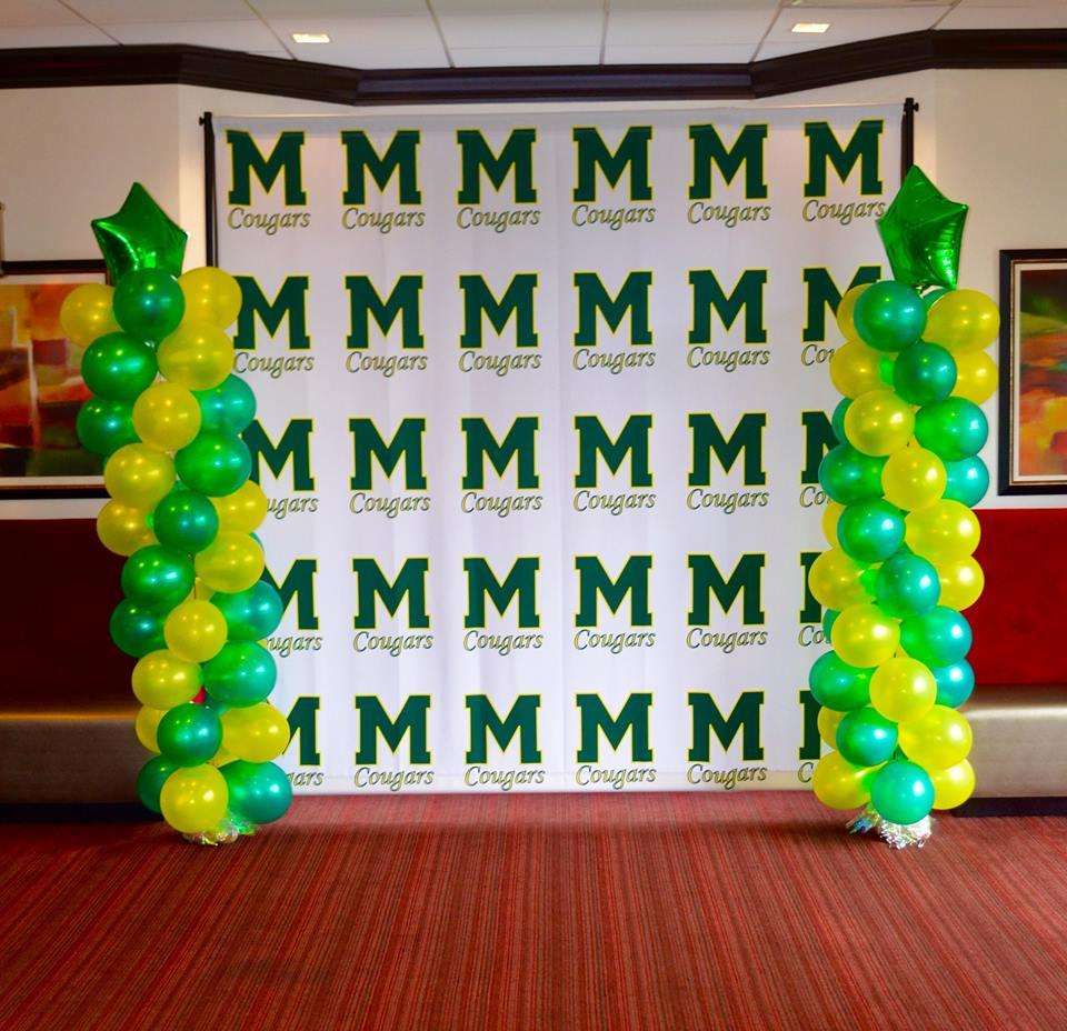 Banner with green logos for the M. Cougars and balloons on either side.