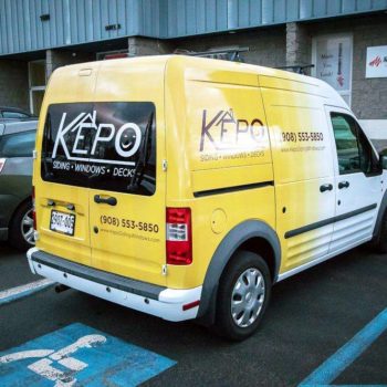 Vehicle wrap on a yellow van for Kepo siding, windows, and doors with home image.