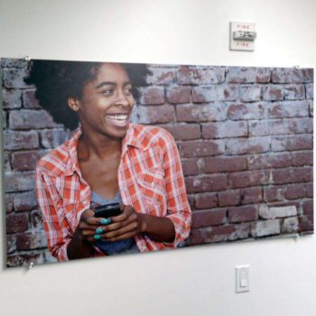 Indoor signage featuring a woman on her phone in front of a brick wall.