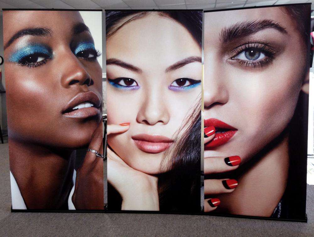 3 women on banners with differing types of colorful makeup, lipstick, and nail polish worn.