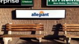 Signs for Enterprise, National, Allegiant, and Fly Frontier on a brick wall