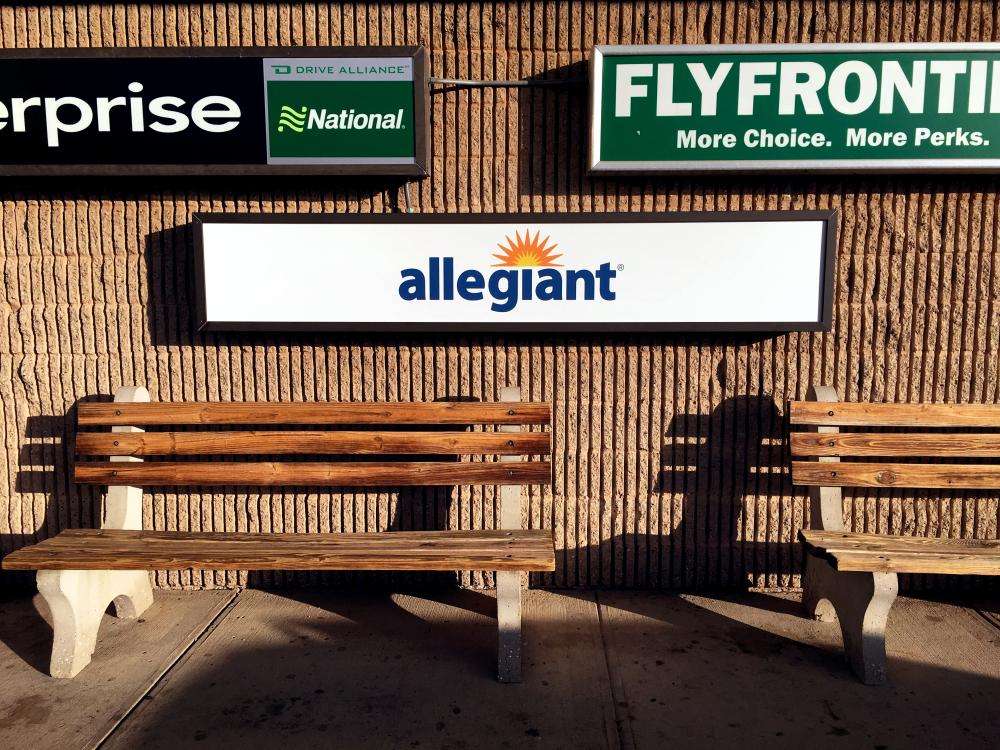 Signs for Enterprise, National, Allegiant, and Fly Frontier on a brick wall