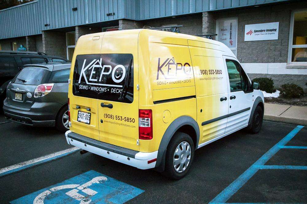 Vehicle wrap on a white van for Kepo siding, windows, and doors with home image.