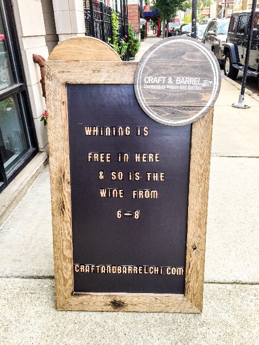 A sidewalk sign advertising free wine at Craft and Barrel