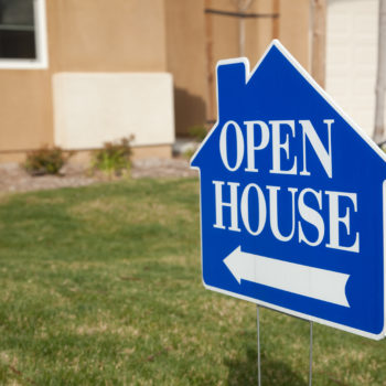 A blue and white yard sign advertising an open house