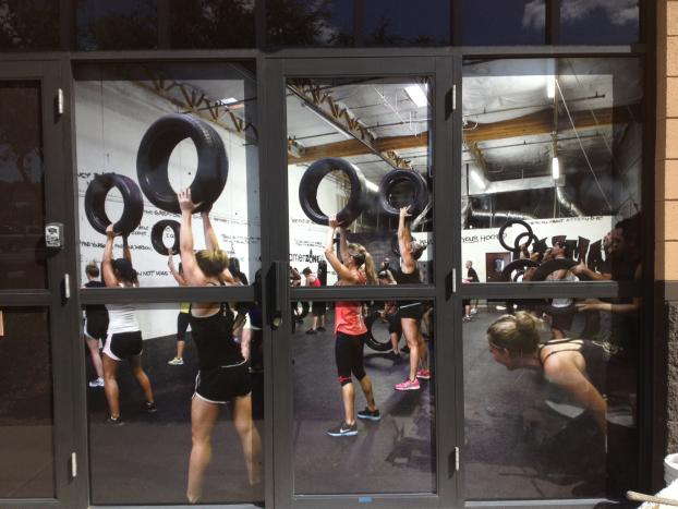 Window graphics of an exercise class where woman are lifting tires. 