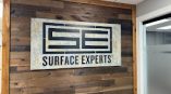Surface Experts interior sign installed on wood wall