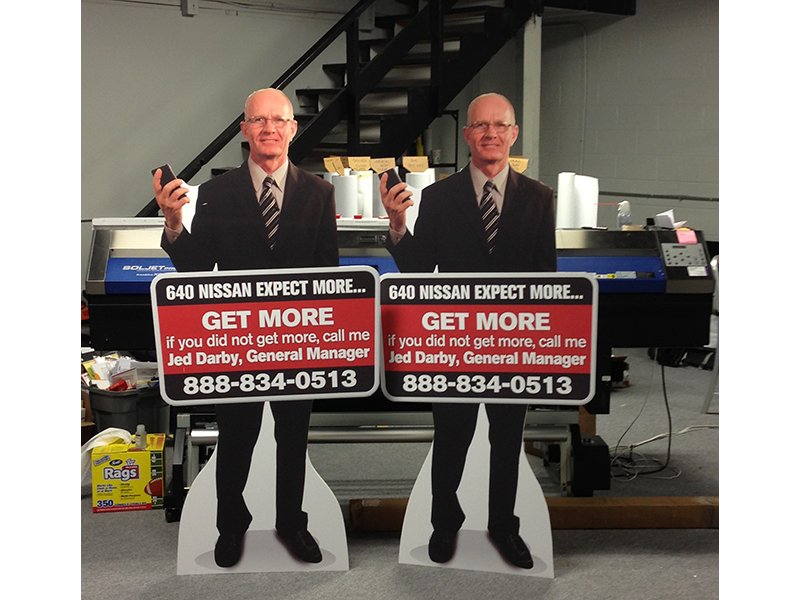 Life-size standees of a white-collar worker with advertising details at dealership