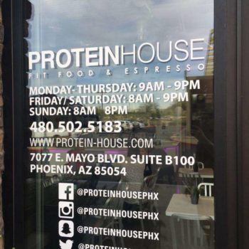 Window sign for Protein House with their hours, location, and social media