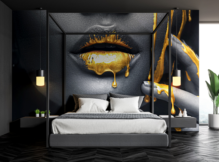 Bed in front of a black and white image of a woman’s lips with gold liquid dripping. 