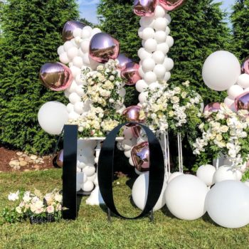 Black number 10 sign with balloons and flowers 