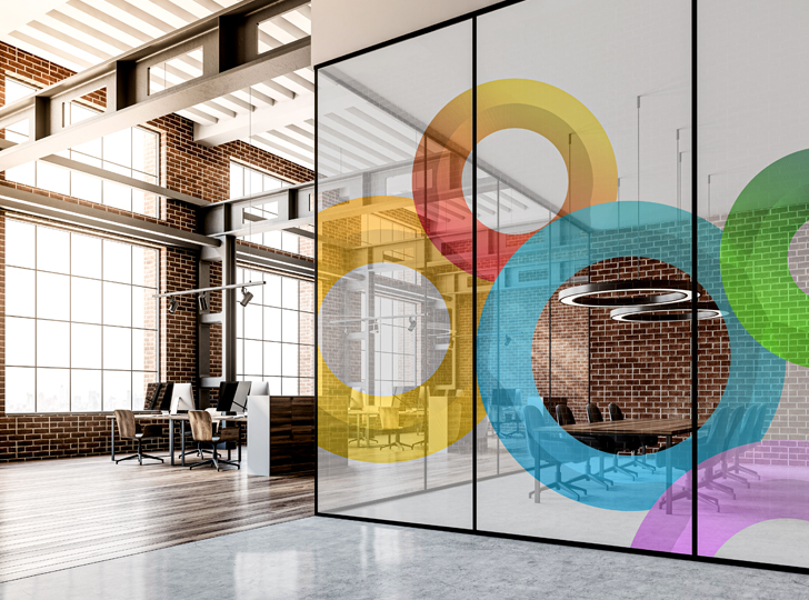 Colorful circle decals on glass partitions in modern office with brick walls.