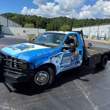 Custom full vehicle wrap on a flatbed truck featuring bold blue graphics.