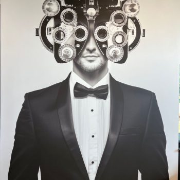 Large wall mural of a man in a tuxedo wearing an eye exam phoropter in Raleigh, NC.