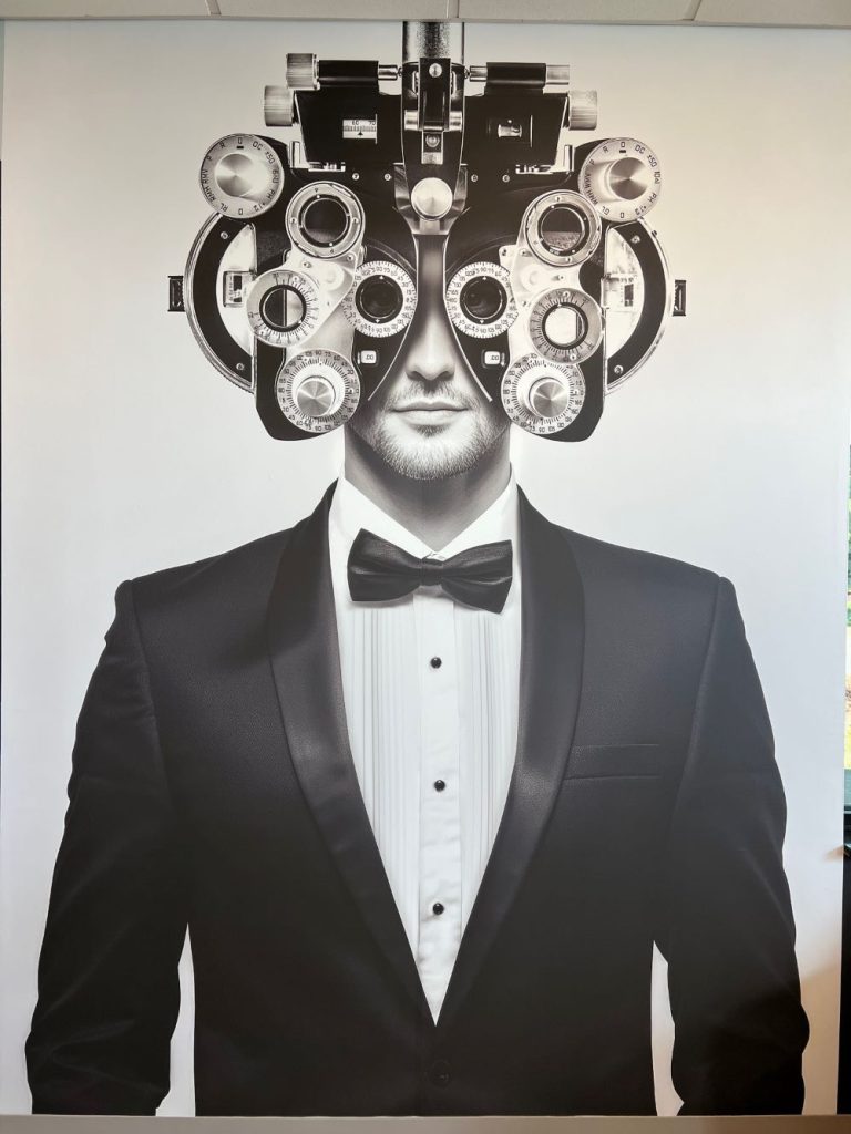Large wall mural of a man in a tuxedo wearing an eye exam phoropter in Raleigh, NC.