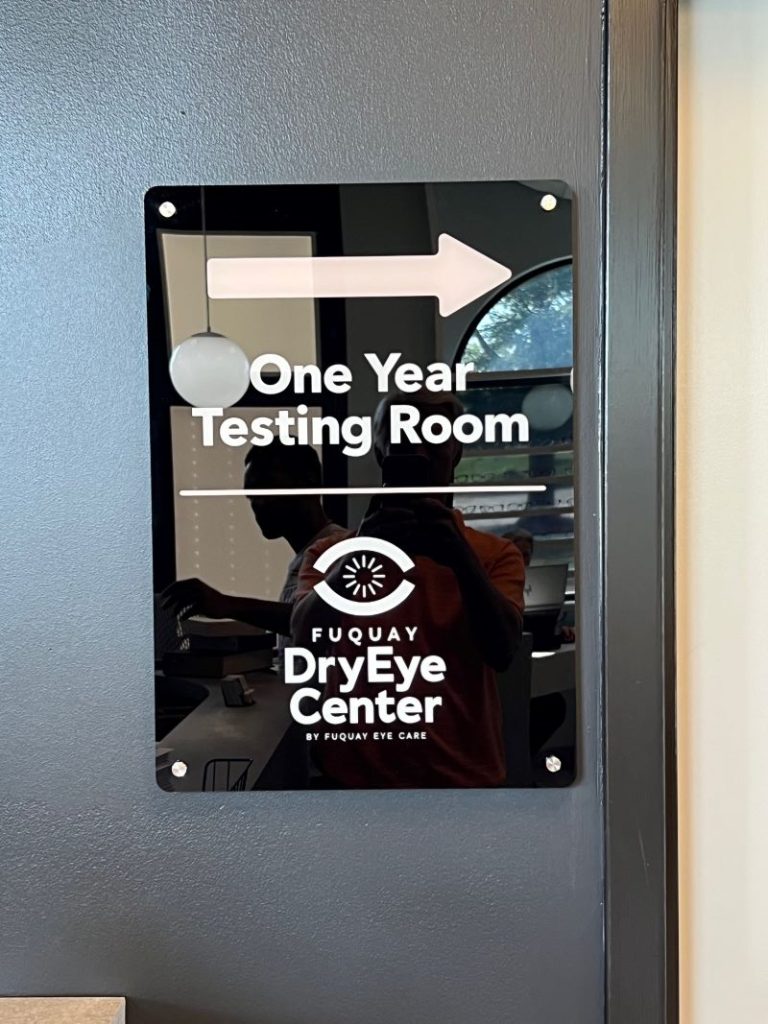 Acrylic directional wall sign with white vinyl lettering mounted on gray wall in Raleigh, NC.
