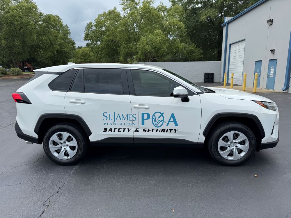 Custom vehicle lettering and logo graphics on a white pickup truck for a property owners association safety and security team.
