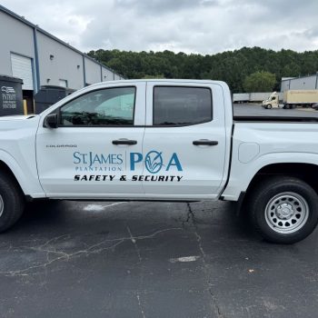 Custom vehicle lettering and logo graphics on a white pickup truck for a property owners association safety and security team.