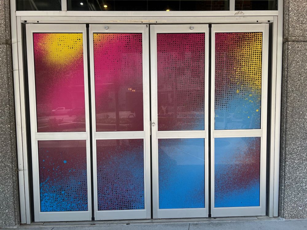 Colorful perforated window film applied on double glass doors with metal frames in Raleigh, NC.