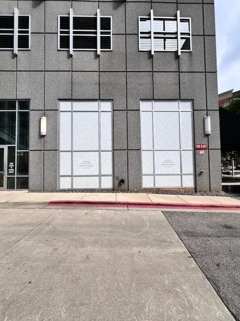 Two large window films with geometric patterns on a gray building exterior in Raleigh, NC.