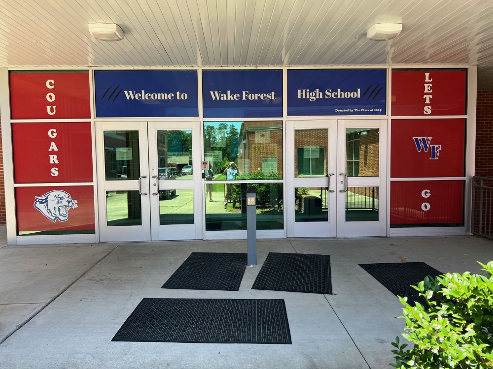 Window film graphics on glass doors and panels at a high school entrance in Raleigh, NC.