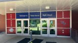 Window film signage with school colors and logos on entrance doors in Raleigh, NC.