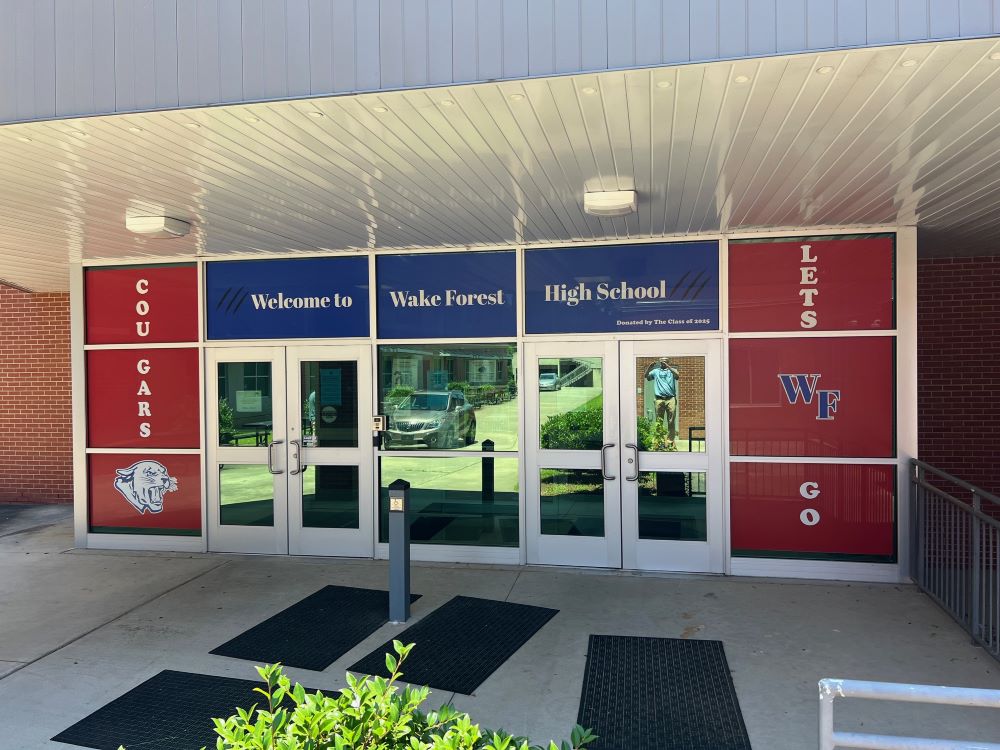 Window film signage with school colors and logos on entrance doors in Raleigh, NC.
