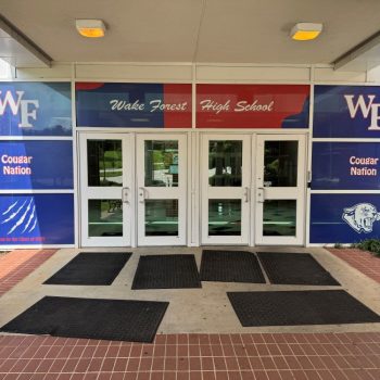 Window film graphics with school logos and colors on entrance doors in Raleigh, NC.